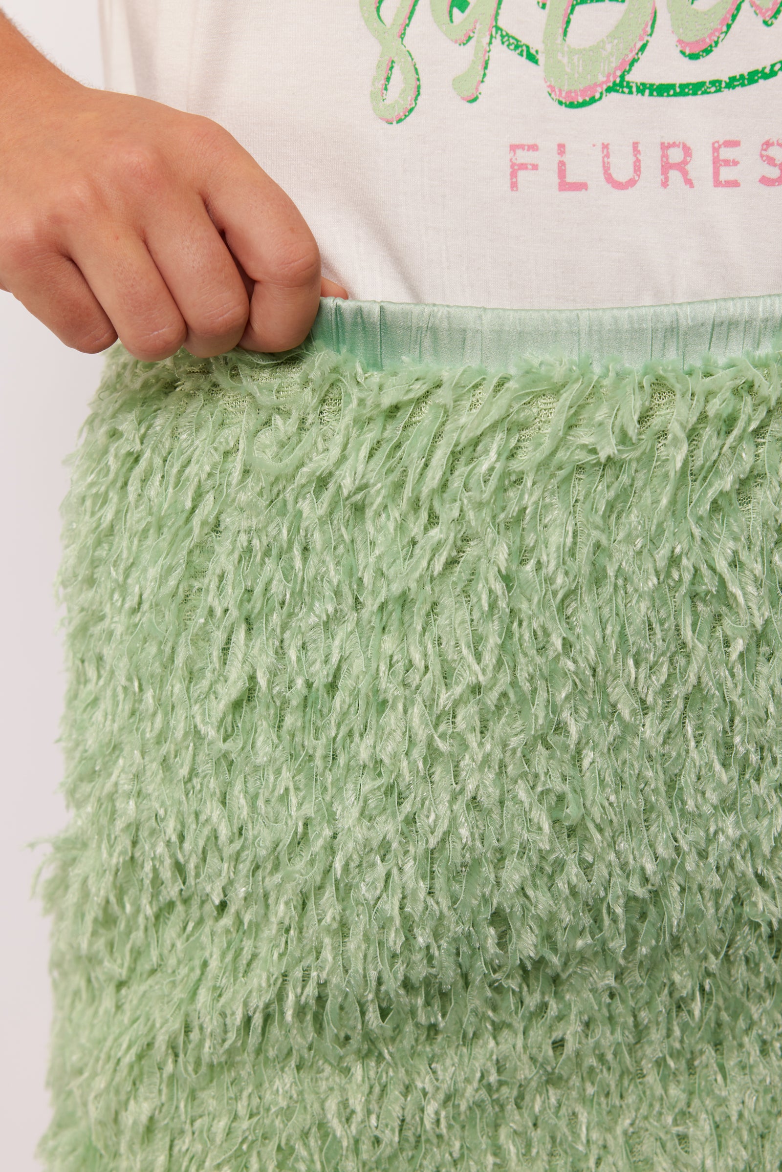 Close-up van de tailleband van de Arianne Skirt van Fluresk, met pluizige groene stof en elastische band.