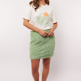 Model draagt de mintgroene Arianne Skirt van Fluresk met een wit T-shirt en oranje sneakers, perfect voor een zomerse casual look.