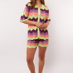 Model draagt de complete co-ord set met Rihanna Shorts en Whitney blouse van Fluresk – kleurrijke zomerse outfit in gehaakt zigzagmotief.