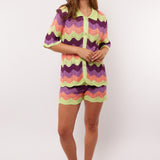 Model draagt de complete co-ord set met Rihanna Shorts en Whitney blouse van Fluresk – kleurrijke zomerse outfit in gehaakt zigzagmotief.