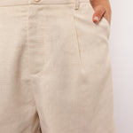 Close-up van de beige Seraphina Shorts met knoopsluiting en steekzakken.
