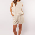 Model draagt de Seraphina Shorts met mouwloze top en oranje sneakers, zomerse outfit.