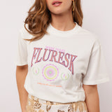 Model draagt het Soraya T-shirt van Fluresk met een witte basis en kleurrijke 'West Coast Fluresk' print.