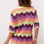 Achteraanzicht van de Whitney Blouse van Fluresk, met kleurrijke zigzagstrepen in paars, lila, perzik en lime.