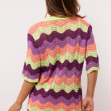Achteraanzicht van de Whitney Blouse van Fluresk, met kleurrijke zigzagstrepen in paars, lila, perzik en lime.