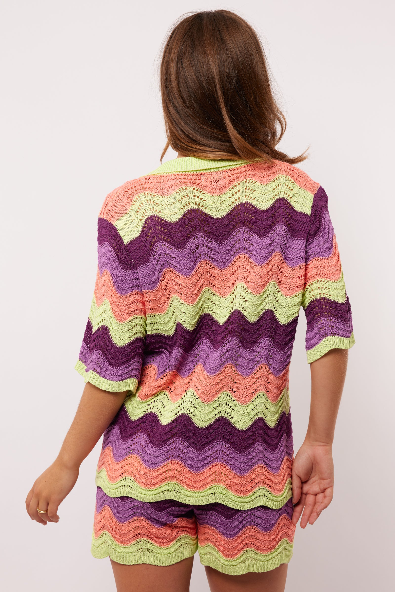 Achteraanzicht van de Whitney Blouse van Fluresk, met kleurrijke zigzagstrepen in paars, lila, perzik en lime.