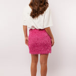Model van achteren met de roze Arianne skirt van Fluresk, gecombineerd met een oversized wit shirt en sneakers.