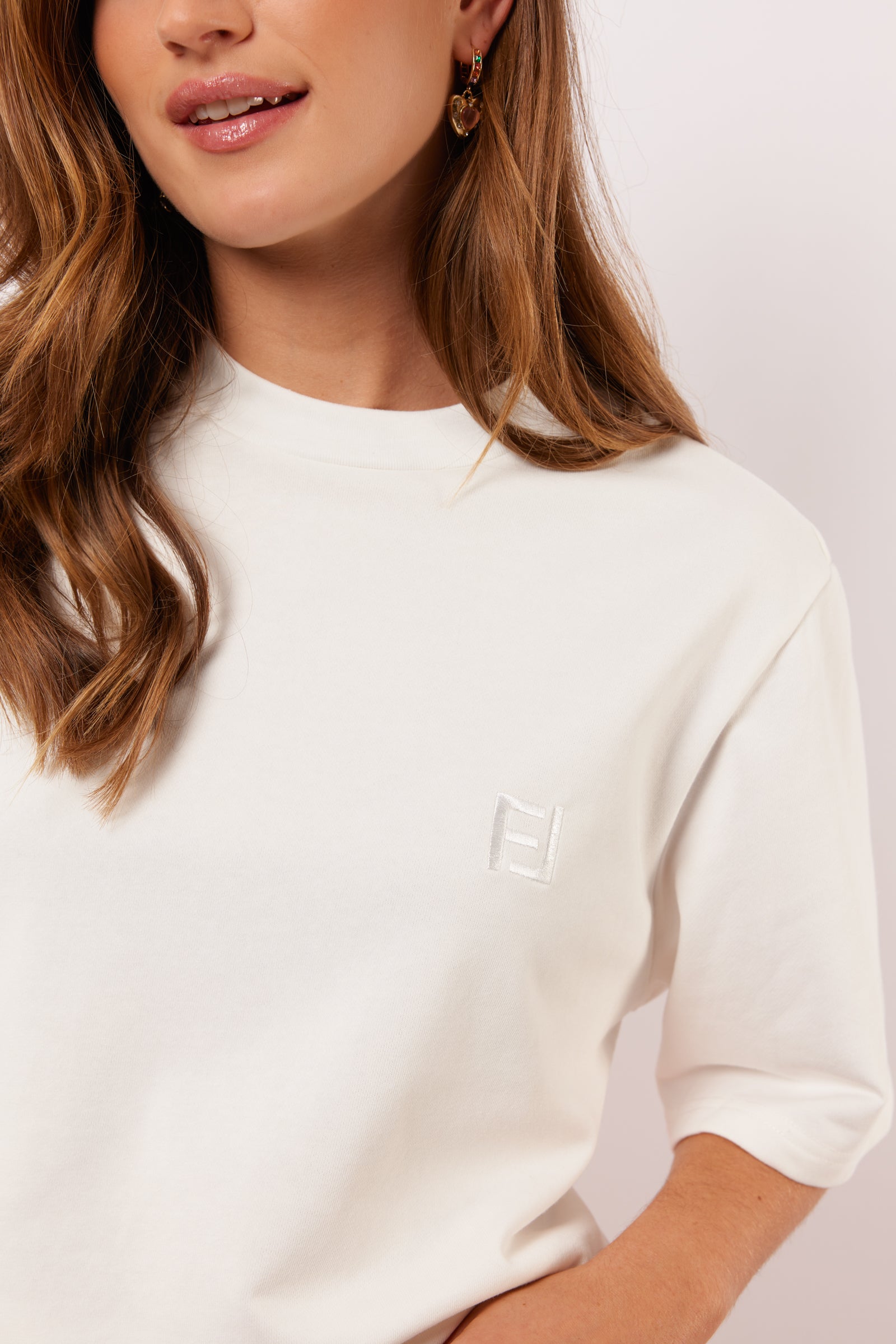 Detail van het witte Fluresk Brix T-shirt met ton-sur-ton geborduurd logo op de borst en subtiele ronde hals.