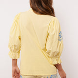 Achterkant van de Fluresk Marlowe blouse in geel met pofmouwen en bijpassende short.