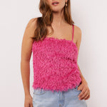Vrouw draagt de Millicent top in felroze met fluffy textuur aan de voorkant en denim short, voor een speelse zomerse look.