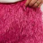 Close-up van de fluffy textuur van de roze Arianne rok van Fluresk, met hand die licht de stof vasthoudt voor detailweergave.