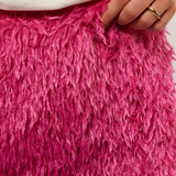 Close-up van de fluffy textuur van de roze Arianne rok van Fluresk, met hand die licht de stof vasthoudt voor detailweergave.