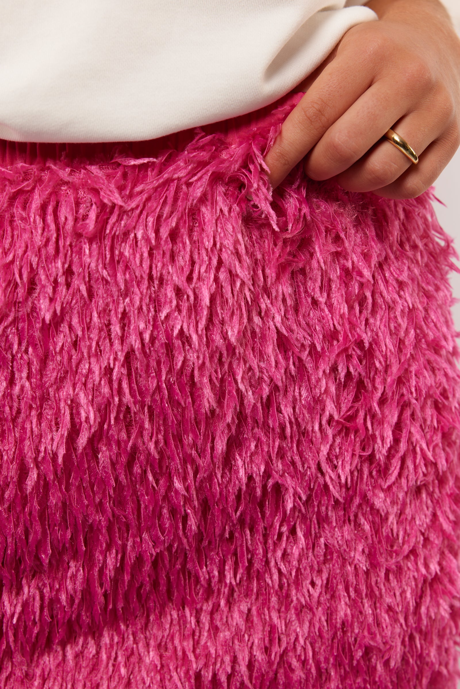 Close-up van de fluffy textuur van de roze Arianne rok van Fluresk, met hand die licht de stof vasthoudt voor detailweergave.